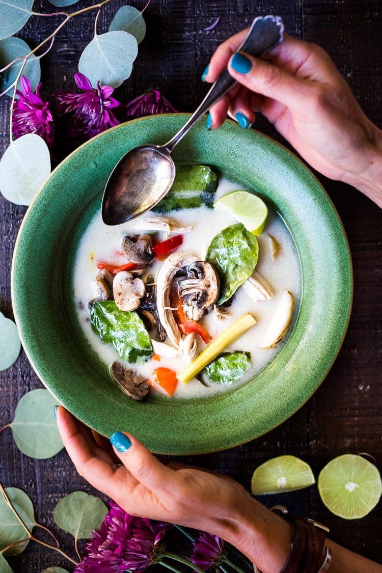 bowl of Tom Kha Gai (Thai Coconut Chicken Soup) with pieces of shredded chicken, lemongrass, lime, kaffir lime leaves, mushrooms, chilies.