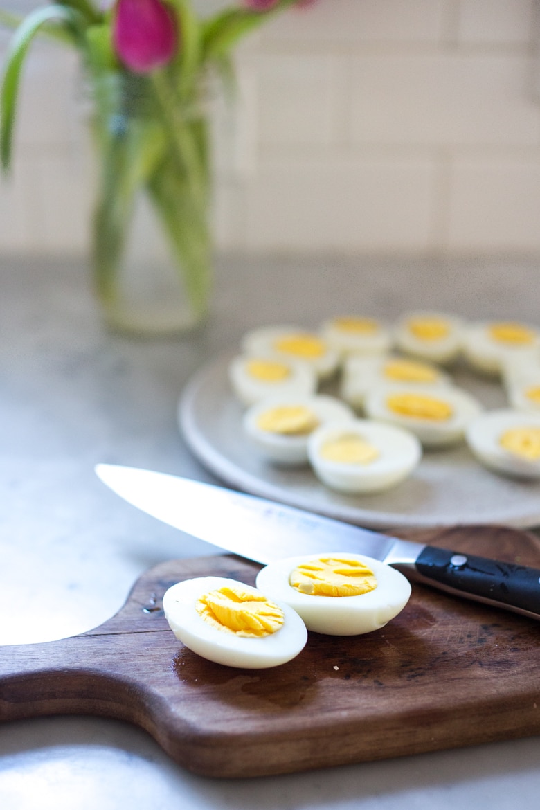 Quick and Easy Hard boiled eggs with olive oil, fresh herbs and pickled shallots, a simple, make ahead brunch recipe that is  perfect for gatherings and potlucks. Think of these like deviled eggs but in ½ the time! #deviledeggs #hardboiledeggs #boiledeggs #brunchrecipe 