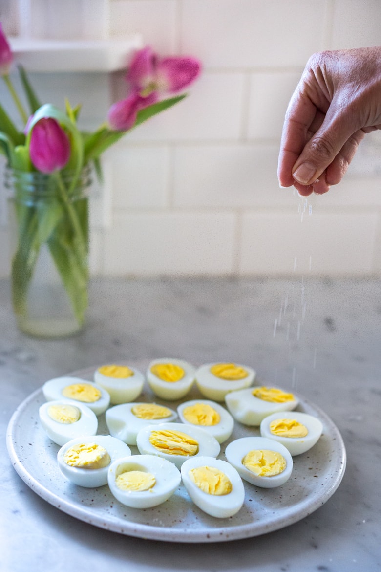 Quick and Easy Hard boiled eggs with olive oil, fresh herbs and pickled shallots, a simple, make ahead brunch recipe that is  perfect for gatherings and potlucks. Think of these like deviled eggs but in ½ the time! #deviledeggs #hardboiledeggs #boiledeggs #brunchrecipe 