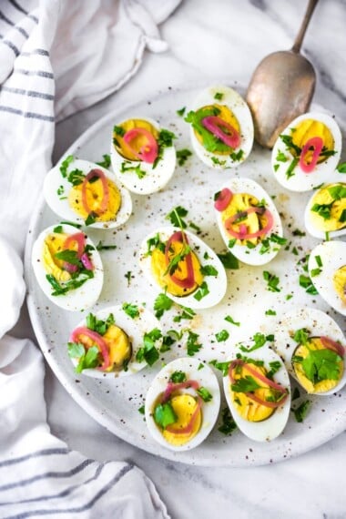 Quick and Easy Hard boiled eggs with olive oil, fresh herbs and pickled shallots, a simple, make ahead brunch recipe that is  perfect for gatherings and potlucks. Think of these like deviled eggs but in ½ the time! #deviledeggs #hardboiledeggs #boiledeggs #brunchrecipe