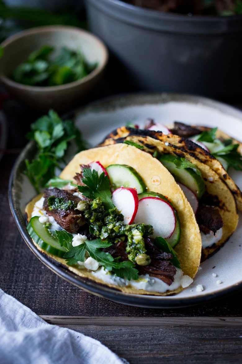 Greek Lamb Tacos with Tzatziki Sauce, cucumber and radishes. A Made with tender, falling off the bone, slow-roasted Lamb shoulder. Delicious flavors! #lamb #lambtacos #lambshoulder #slowroasted #braisedlamb www.feastingathome.com