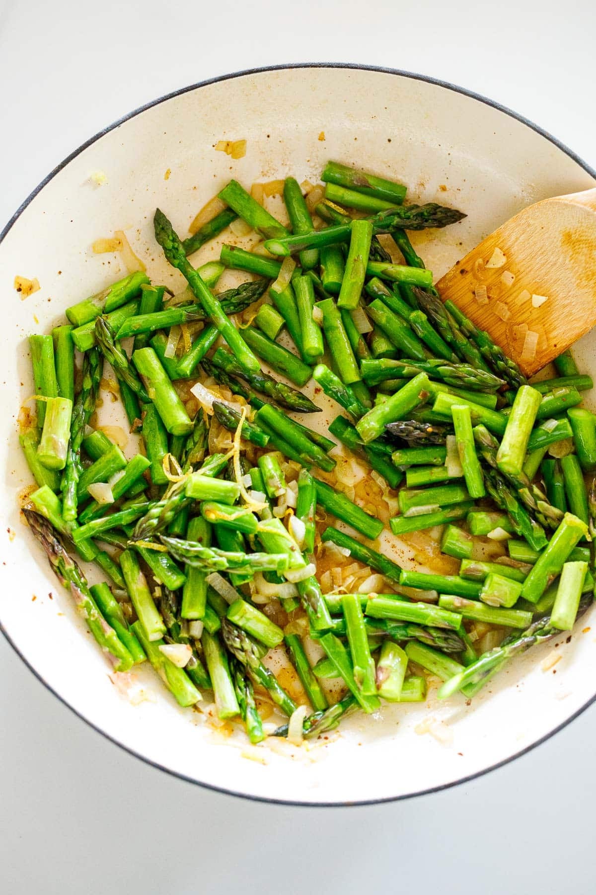 pan with chopped asparagus with shallots, sautéing with wood spatula. 
