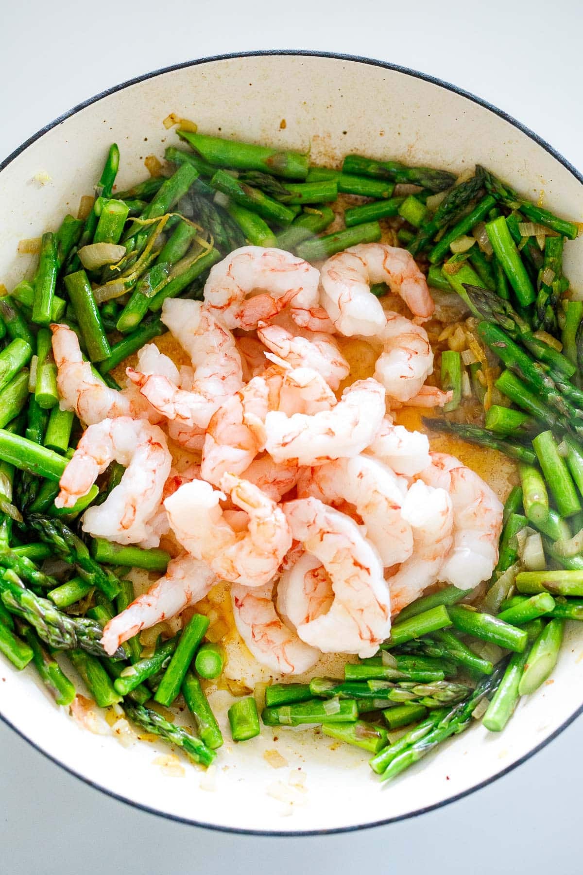 pan with shrimp in center, surrounded by sautéed asparagus.