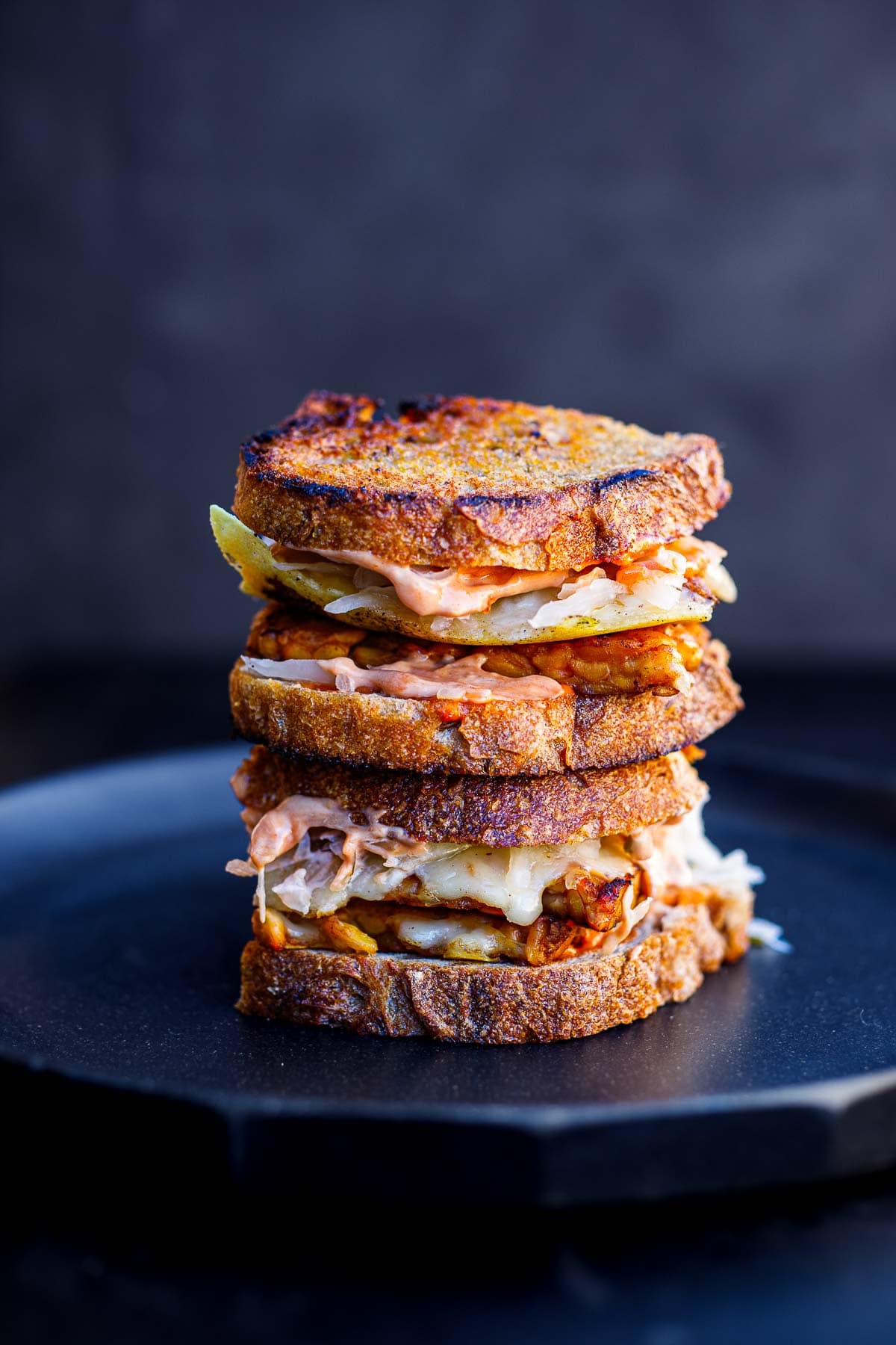a tempeh reuben sandwich, stacked on a plate. 