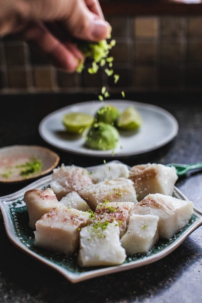 hand sprinkling lime zest on fish fillets. 