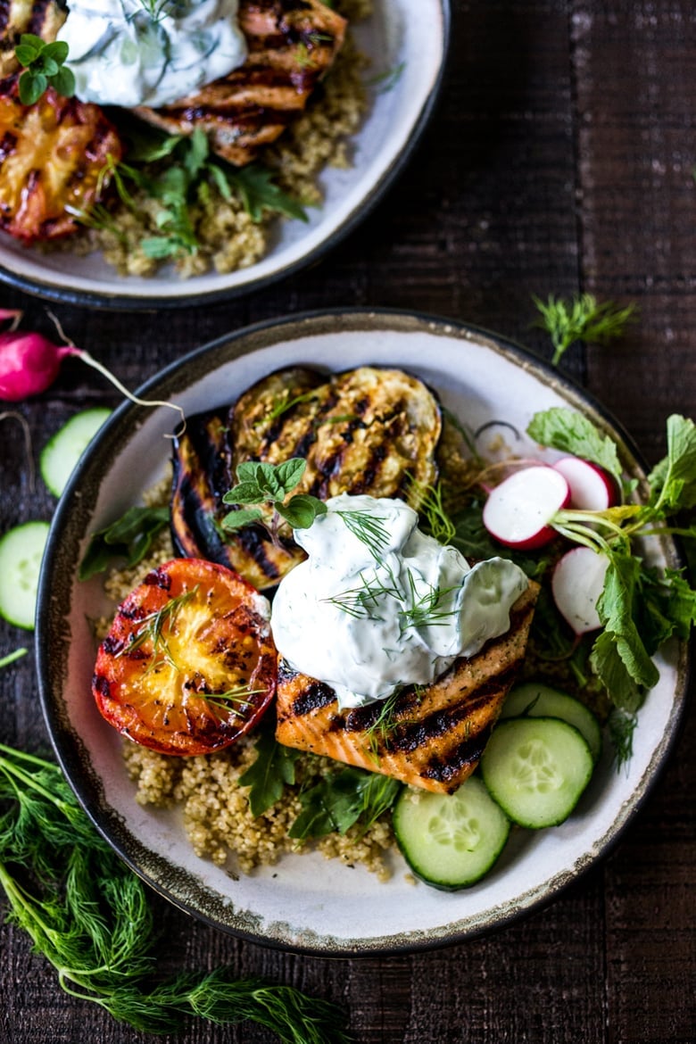 Mediterranean Grilled Salmon and grilled summer veggies over quinoa, and fresh greens, topped with a dollop of creamy Tzatziki Sauce.