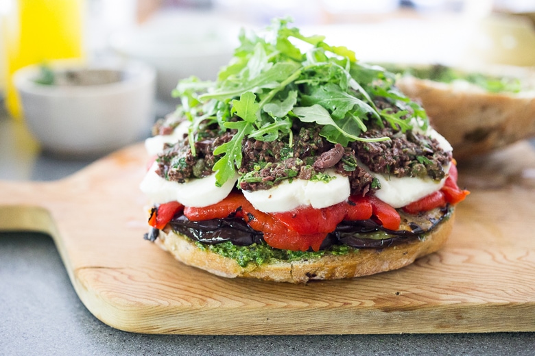 Grilled Eggplant Muffuletta Sandwich with Pesto, roasted peppers, olive tapenade and fresh mozzarella. All the flavors of summer in one bite! | www.feastingathome.com