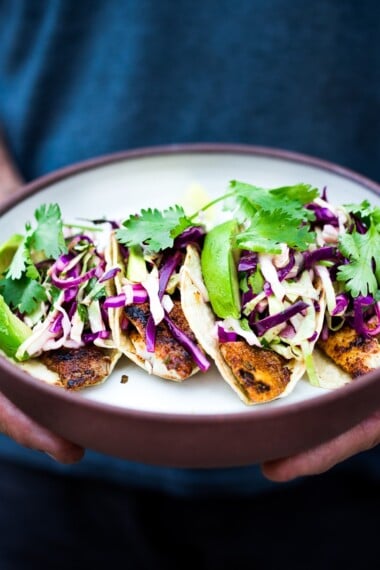 These Fish Tacos with Cilantro Lime Cabbage Slaw are quick, easy, and have the BEST Flavor! Pan-sear, grill or bake in under 30 minutes. Vegan-adaptable swapping tofu for the fish! Video.