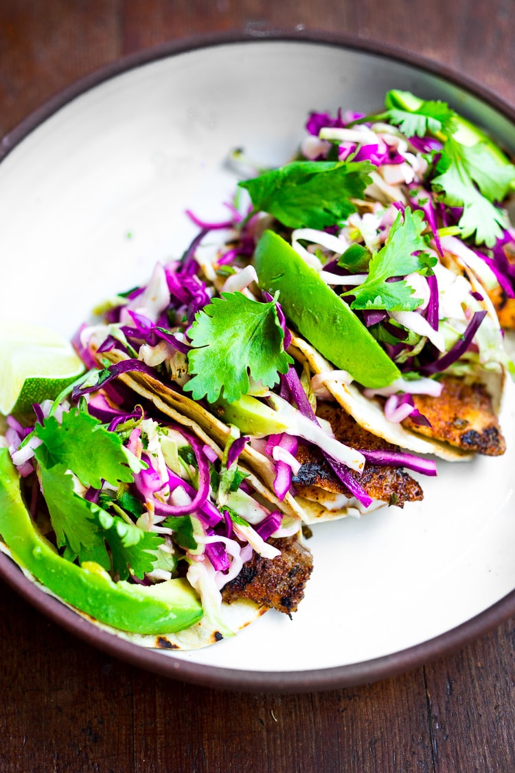 Perfect Fish Tacos with Cilantro Lime Cabbage Slaw are quick, easy, and have the BEST Flavor! Pan-sear, grill or bake in under 30 minutes. Vegan-adaptable swapping tofu for the fish! Video.