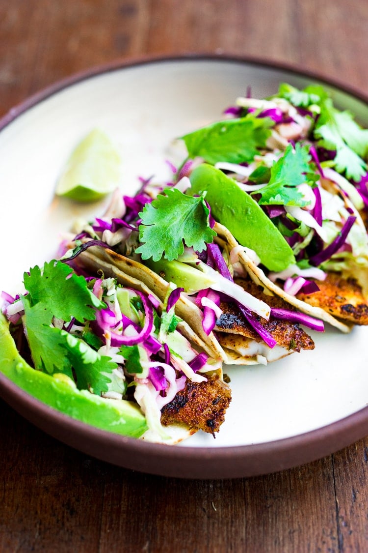 These Fish Tacos with Cilantro Lime Cabbage Slaw are quick, easy, and have the BEST Flavor! Pan-sear, grill or bake in under 30 minutes. Vegan-adaptable swapping tofu for the fish! Video.