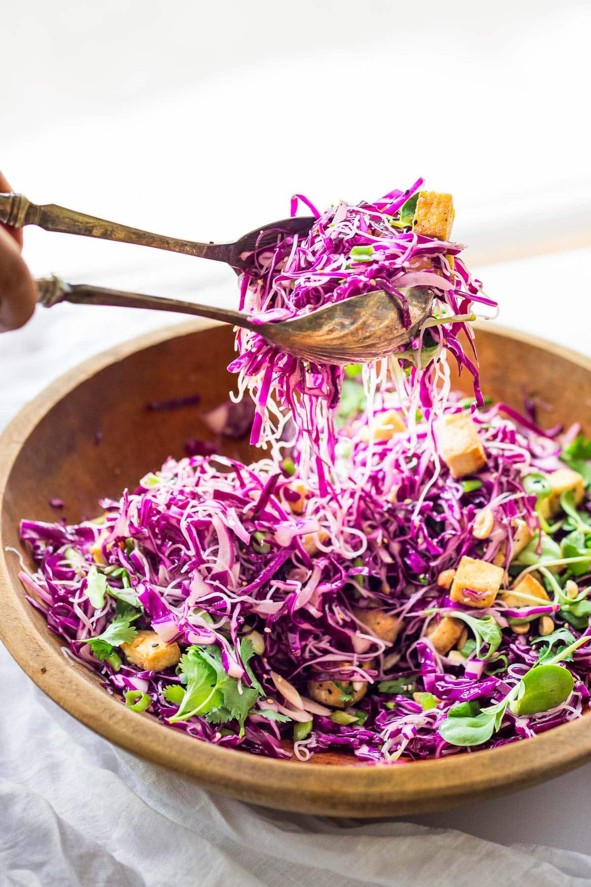 Tossing Asian noodle salad with purple cabbage.