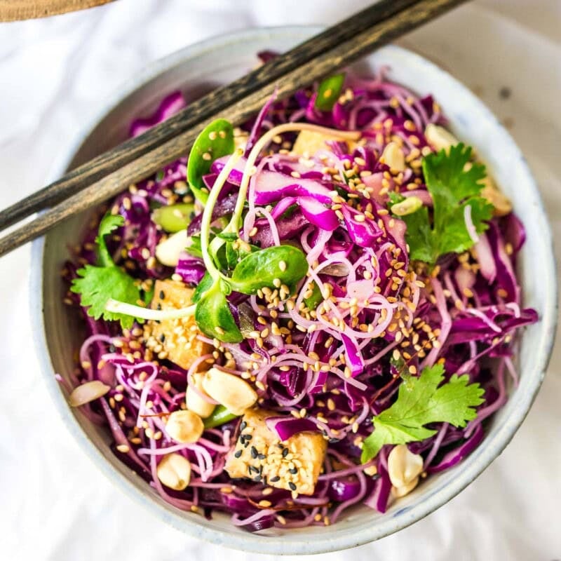 This Asian noodle salad is so tasty! Made with shredded purple cabbage, rice noodles, crispy tofu, scallions, cilantro, and crunchy roasted peanuts in a delicious Asian Dressing. Vegan, Gluten-free!