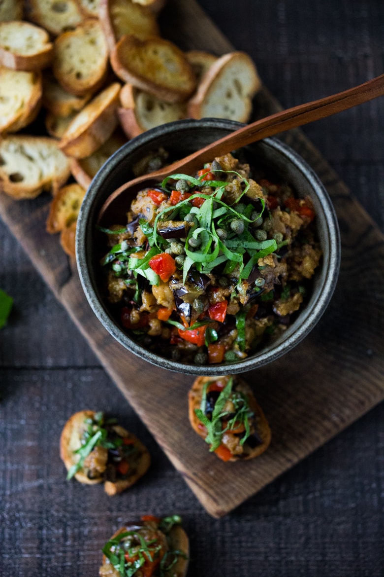 This Sicilian recipe for Eggplant Caponata- is simple, easy and full of summer flavor! Serve it as a healthy vegan appetizer over crostini, or as a delicious side dish, or turn it into an eggplant "salad" served over greens and grains! Low- Carb  and Vegan! #eggplantrecipes #eggplantcaponata #caponata #feastingathome #grilledeggplant #vegan #healthy 
