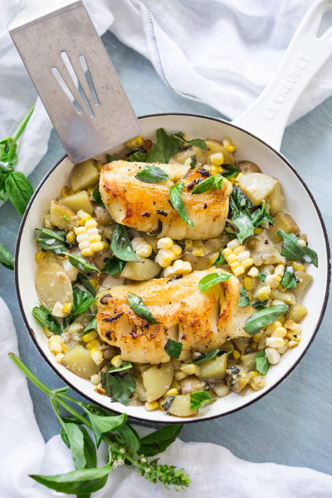 seared white fish in a pot of fresh corn chowder with fresh basil.