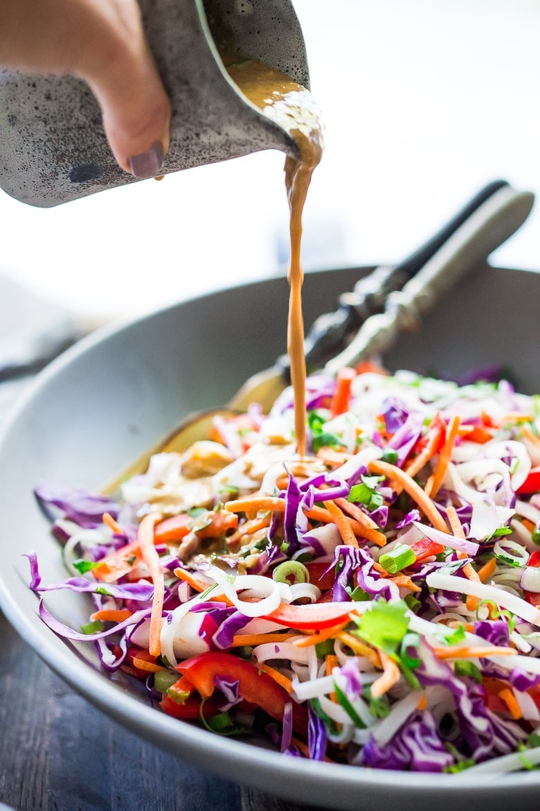 Peanut Sauce being poured into a bowls with the Thai Noodle Salad.