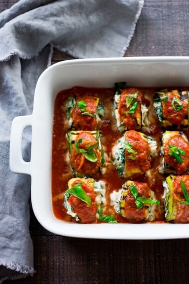 Zucchini Rolls with Spinach and Basil, baked in marinara sauce and topped with optional smoked mozzarella.