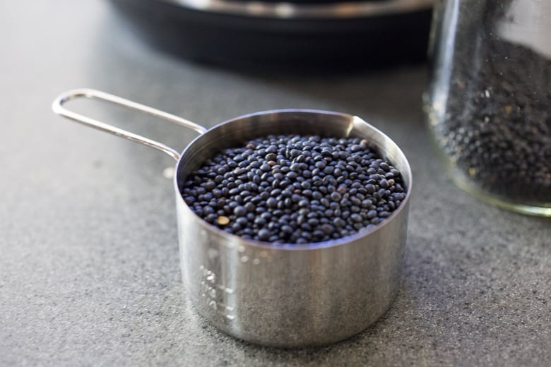 Black lentils in a measuring cup for instant pot lentil soup.