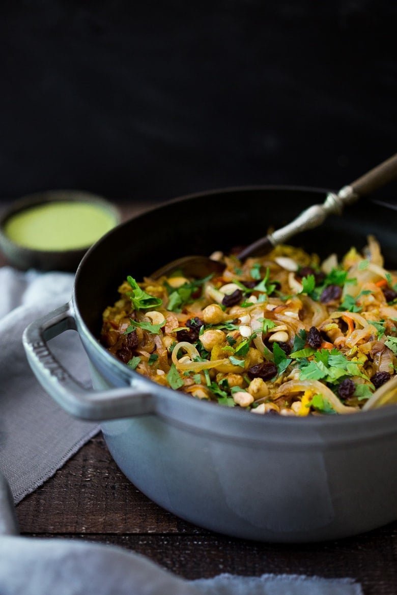 Vegetarian Biryani Vegetable biryani in a dutch oven with onions, raisins and coriander leaves.