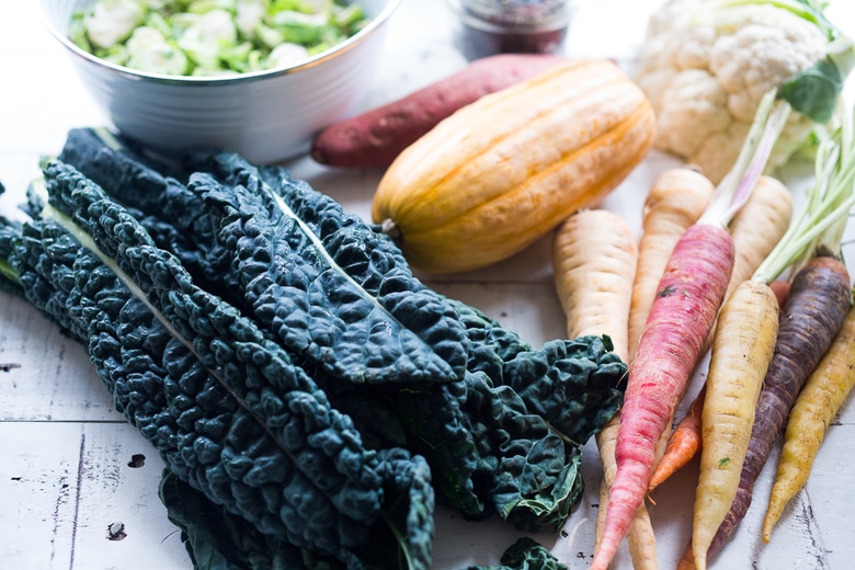 A hearty, healthy Roasted Fall Vegetable Salad with Maple Curry Vinaigrette on a bed of shredded kale and brussel sprouts. Vegan and GF. | www.feastingathome.com