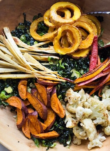 A hearty, healthy Roasted Fall Vegetable Salad with Maple Curry Vinaigrette on a bed of shredded kale and brussel sprouts. Vegan and GF.