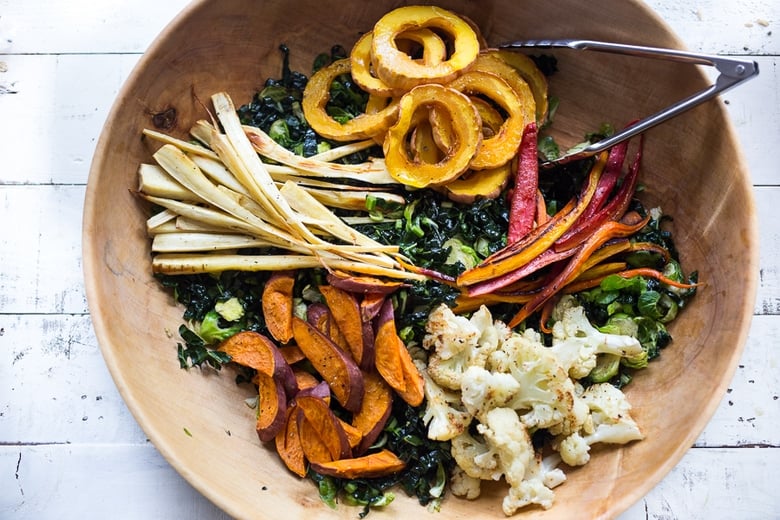 A hearty, healthy Roasted Fall Vegetable Salad with Maple Curry Vinaigrette on a bed of shredded kale and brussel sprouts. Vegan and GF. | www.feastingathome.com