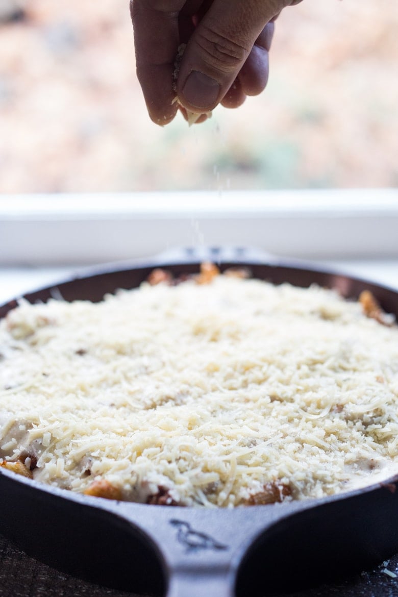 pastitsio in skillet topped with layer of parmesan cheese.