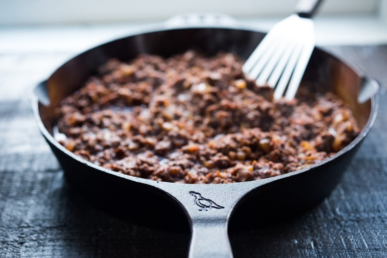 lamb bolognese sauce stewing in cast iron skillet.