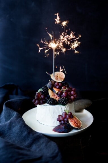 A simple Brie Cake topped with fresh berries, figs and grapes, drizzled with honey and served with seeded crackers -  an easy, festive appetizer or dessert, perfect for parties, celebrations and gatherings.  | #briecake #newyearseve #partyappetizers #appetizers www.feastingathome.com