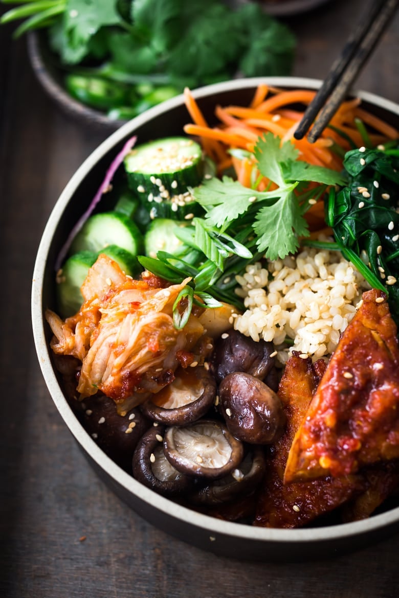 Our 25 BEST Vegan Buddha Bowls!| This Korean -inspired bowl is made with Gochujang baked Tempeh, steamed veggies, kimchi and pickled cucumbers- a healthy vegan version of Bibimbap! #veganbowl #buddhabowls #vegan #plantbased #eatclean #cleaneating #detoxrecipes #detox #plantbased #healthybowls #bibimbap #veganbibimbap