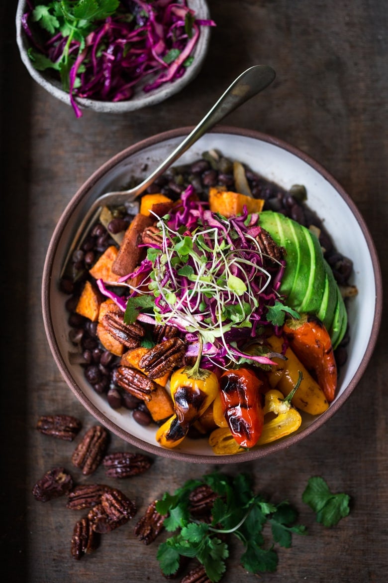  Vegan Mexican-style, Oaxacan Bowl with roasted chipotle sweet potatoes and sweet peppers over a bed of warm seasoned black beans. Topped with a crunchy cabbage slaw, avocado and toasted Chipotle Maple Pecans. | www.feastingathome.com