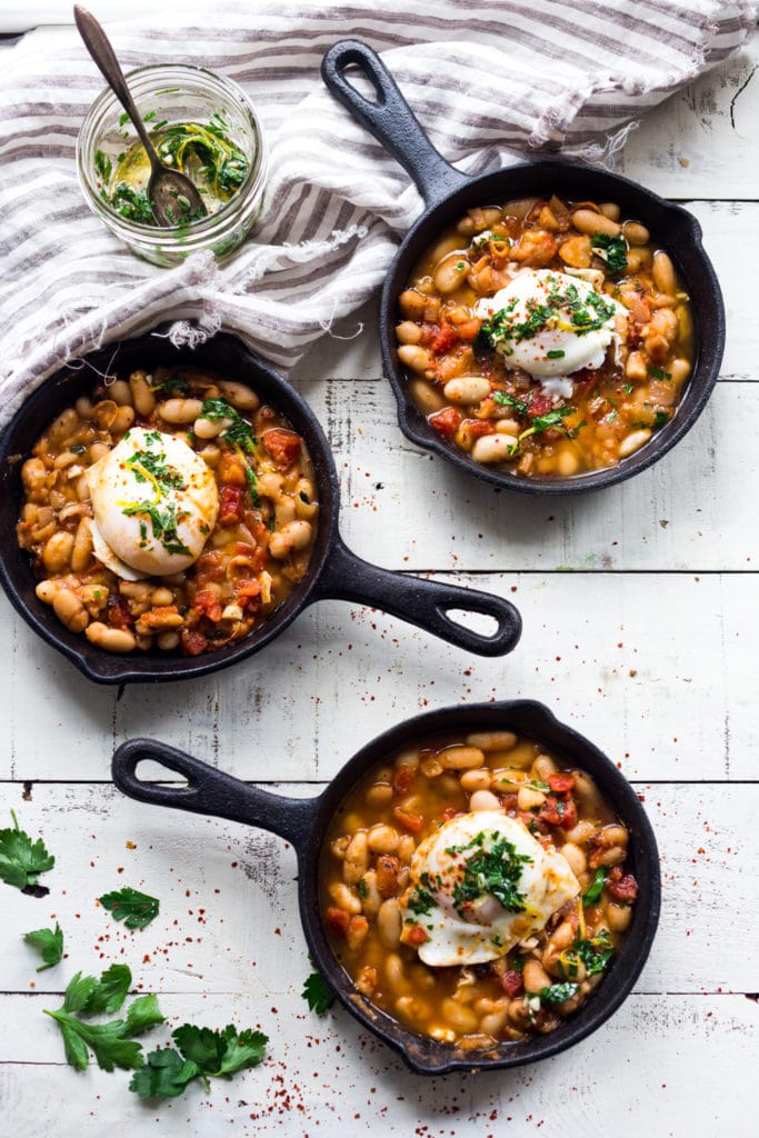 three mini cast iron skillets with Tuscan breakfast - cannellini bean stew topped with poached eggs and gremolata. 