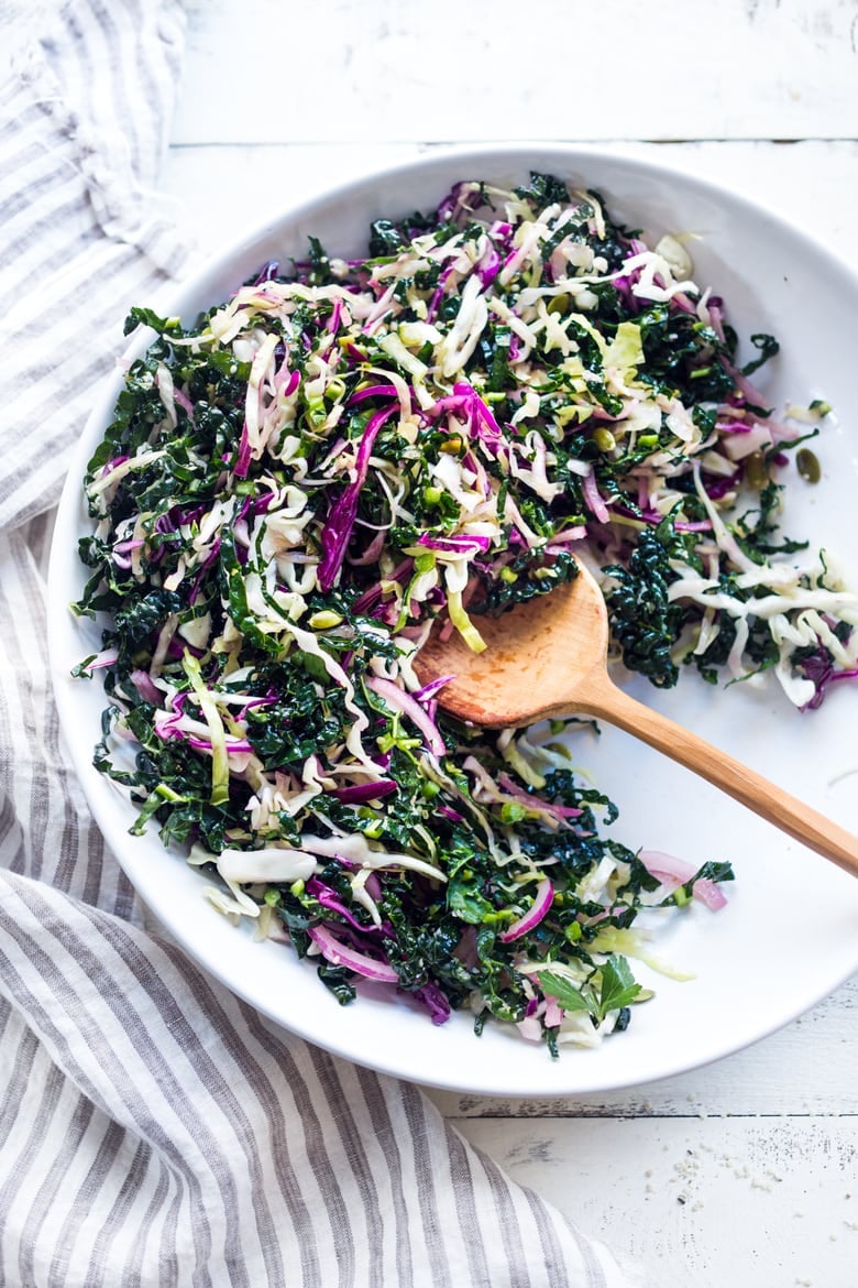 This simple Kale Slaw with Lemony Dressing can be made ahead, then used throughout the week to top off tacos, wraps, buddha bowls, burgers, and even pizza. An easy way to get in your dark leafy greens.  Vegan and Gluten-Free, this amazing kale slaw keeps up to 4 days in the fridge.