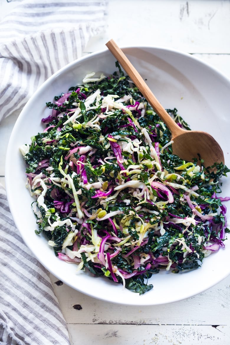 This simple Kale Slaw with Lemony Dressing can be made ahead, then used throughout the week to top off tacos, wraps, buddha bowls, burgers, and even pizza. An easy way to get in your dark leafy greens.  Vegan and Gluten-Free, this amazing kale slaw keeps up to 4 days in the fridge.