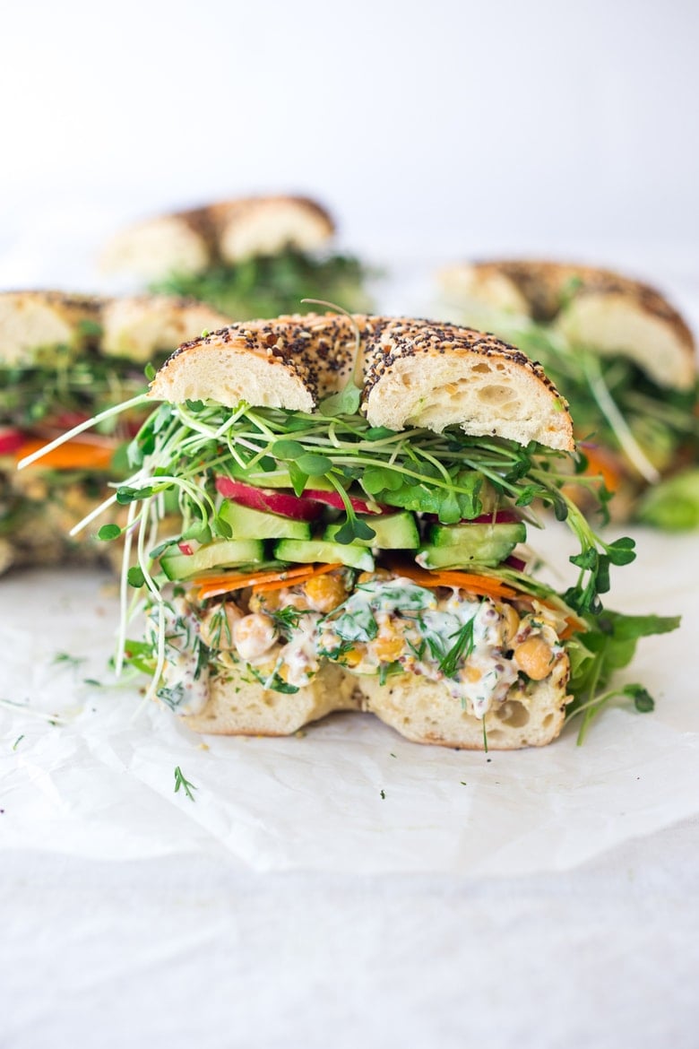 Vegan Chickpea Salad Sandwich on a bagel with avocado, cucumber, microgreens, carrots. 