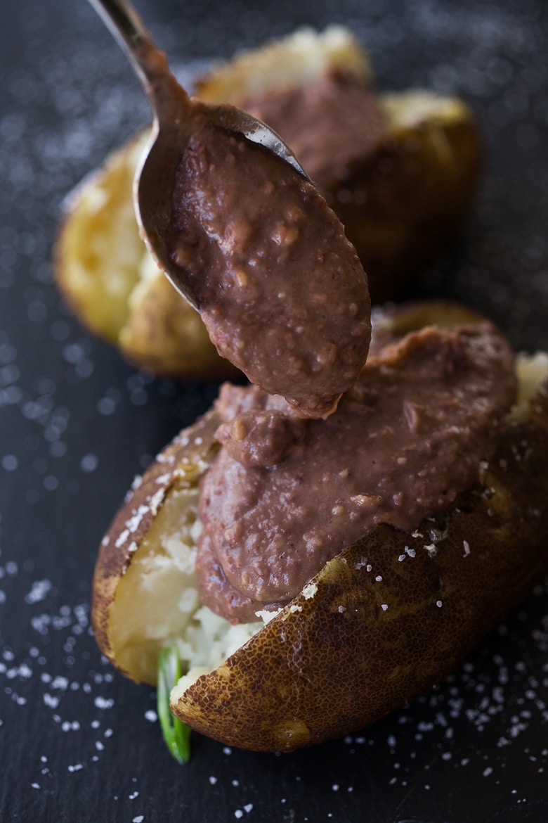 Mexican Baked Potatoes with refried black beans, avocado, jalapeño and Vegan Cilantro Crema - rich and creamy without the addition of butter, dairy or nuts. | #vegan #bakedpotato #mexican