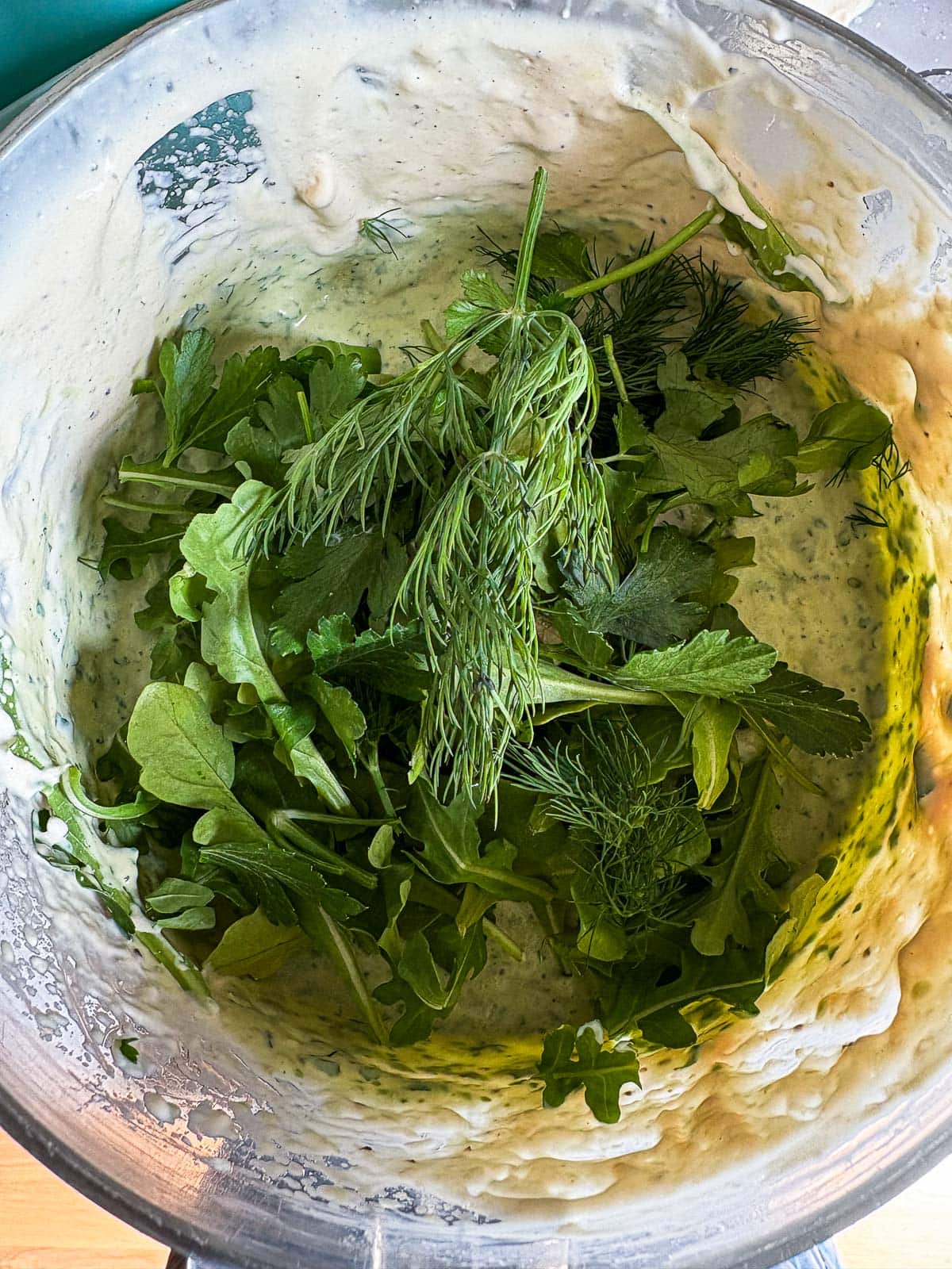 food processor with fresh herbs to make green goddess dressing.