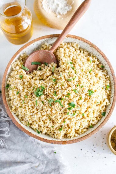 fluffy quinoa in a bowl with a wood spoon.
