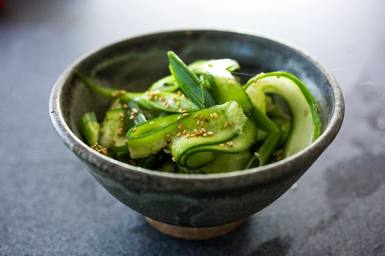 small bowl with cucumber ribbon salad, topped with toasted sesame seeds.