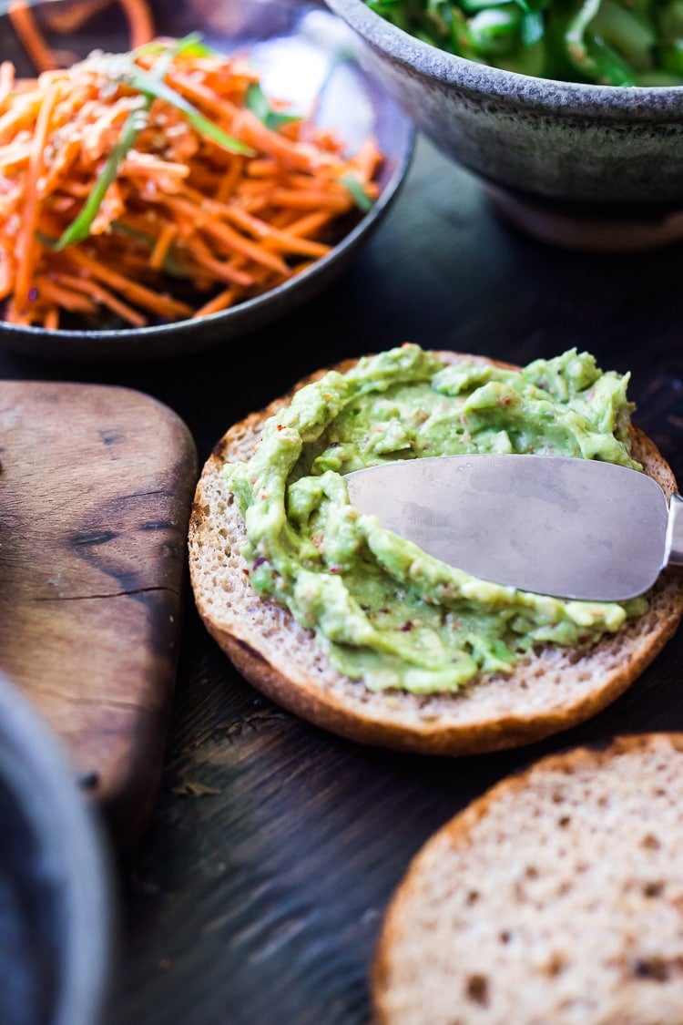 spreading Asian guacamole on grilled wheat bun to assemble portobello mushroom burgers.