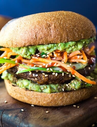 This Asian-style, grilled, vegan portobello mushroom burger is full of delicious umami flavor! It's lathered with Asian-style Guacamole, topped with a cool cucumber ribbon salad and crunchy carrot slaw. Healthy, delicious and really satisfying. AND totally vegan! #veganburger #portobelloburger #veganportobelloburger #portobellomushroomrecipes #portobello #vegan #veganburger #grilled #grilledportobello