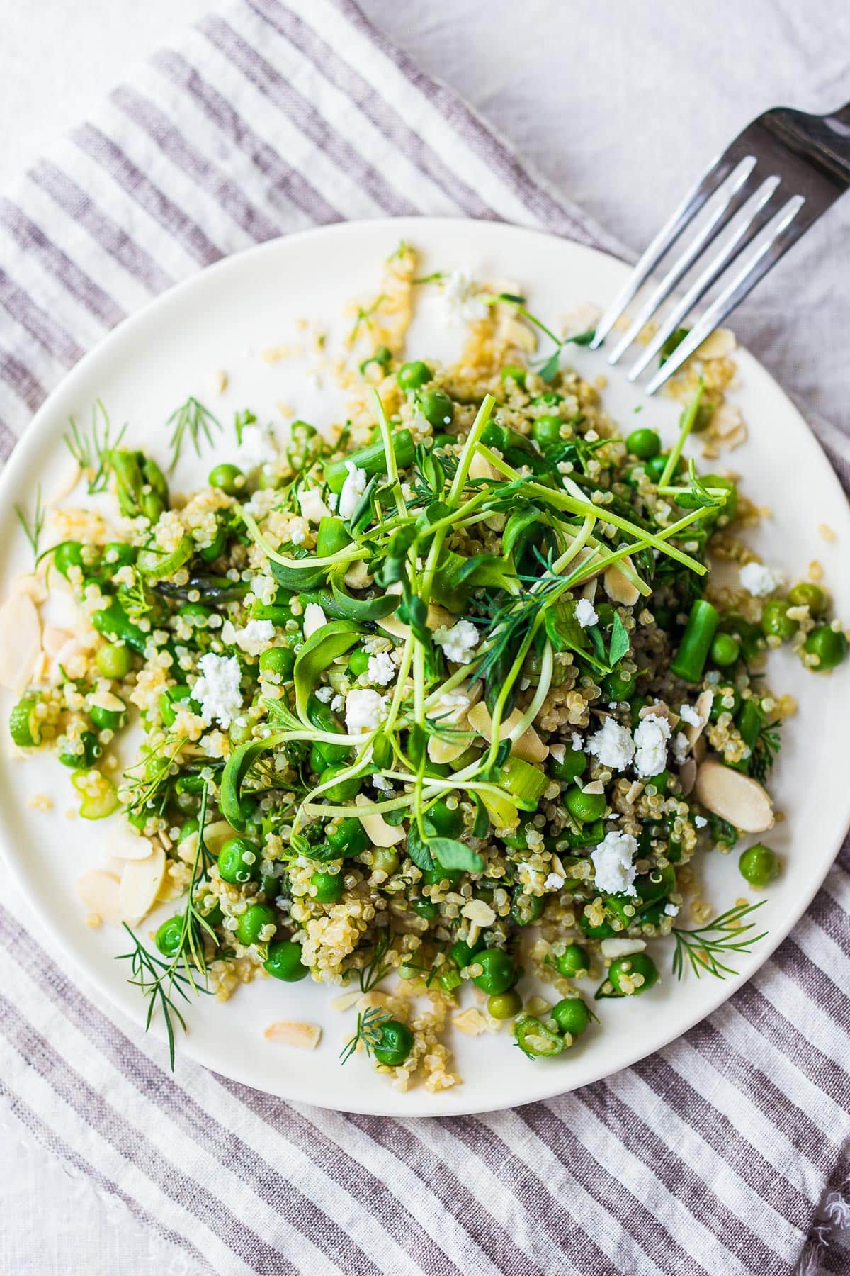 A simple recipe for Quinoa Asparagus Salad (aka Spring Tabouli) tossed with English peas, fresh dill, parsley, toasted almonds in a lemony dressing topped with optional avocado, goat or feta cheese. A healthy, flavorful salad that can be made ahead- perfect for special gatherings or midweek lunches! GF &  Vegan adaptable! 
