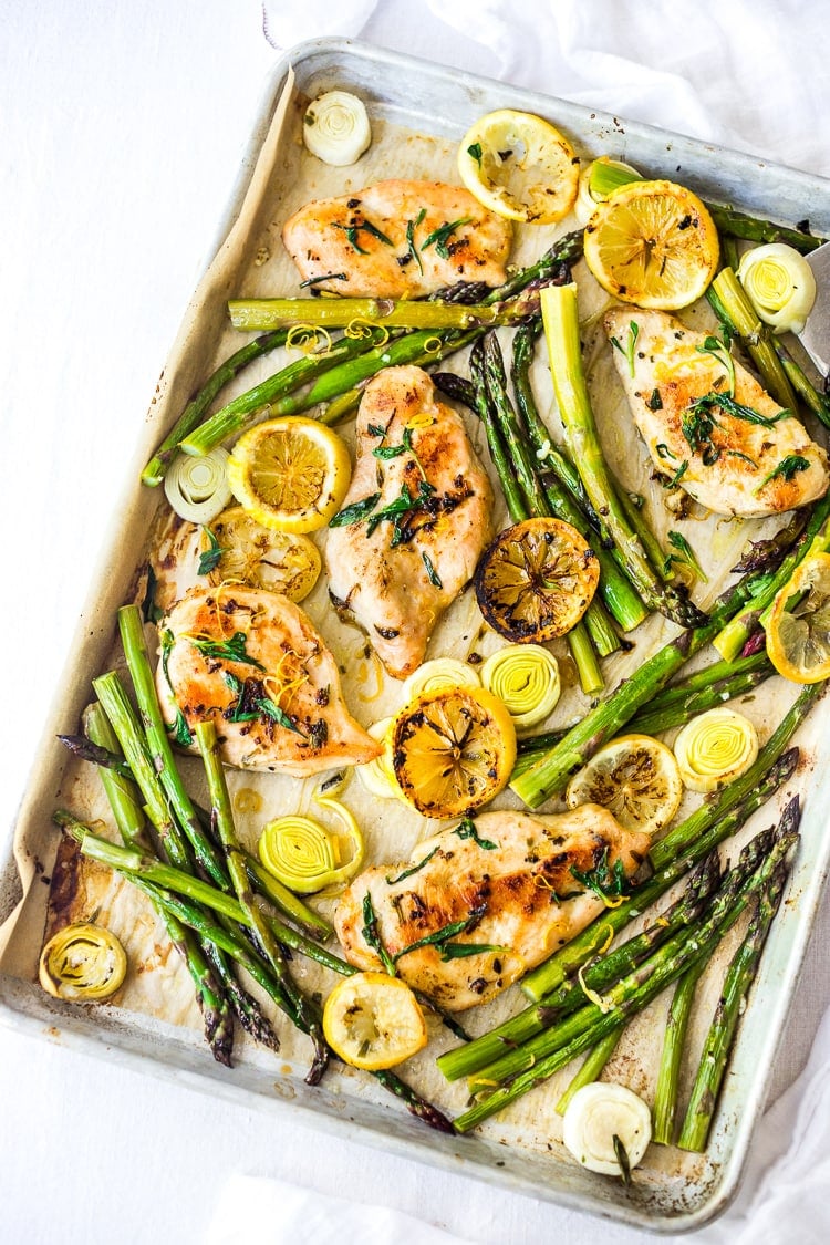 parchment-lined sheet pan with tarragon chicken with asparagus, lemon and leeks.