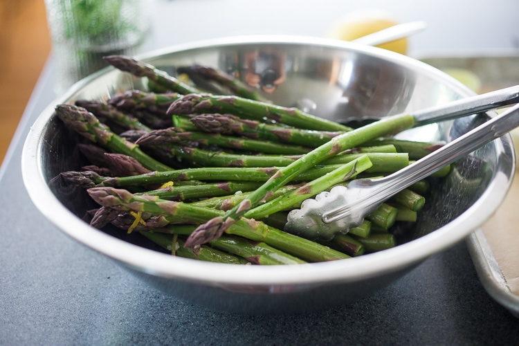 trimmed asparagus in mixing bowl with lemon tarragon marinade.