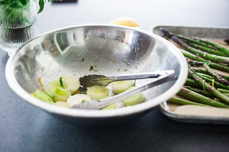 sliced leeks in mixing bowl with lemon tarragon marinade.