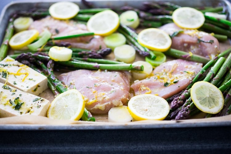 sheet pan with chicken breasts, tofu, asparagus, lemon slices, and leeks in lemon tarragon marinade.