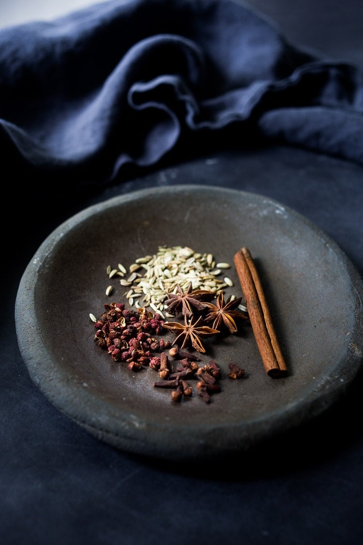 small dish with whole spices for Chinese Five Spice- fennel seeds, cinnamon stick, whole cloves, star anise, and szechuan peppercorns.