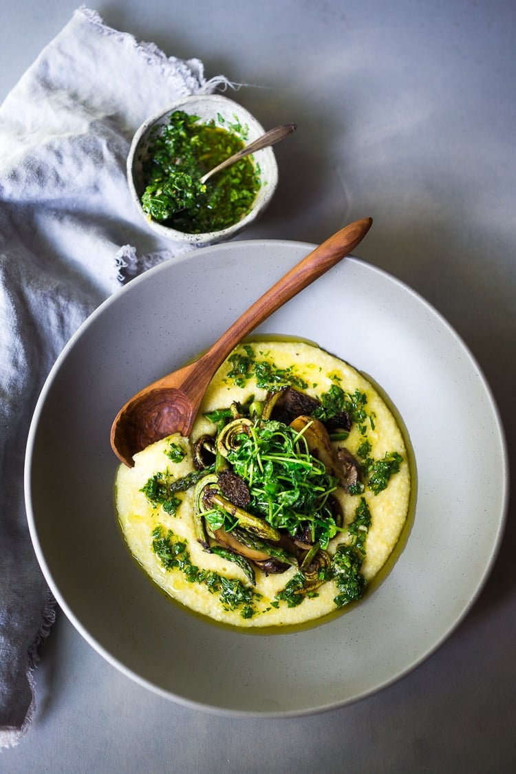 Creamy Polenta with Spring Veggies and Gremolata - a simple healthy VEGAN recipe featuring vibrant spring produce that can be made in under 30 minutes. Vegan & Gluten Free! #creamypolenta #vegan #springrecipes #asparagus #fiddleheadferns #morel #porcini #softpolenta #veganpolenta 