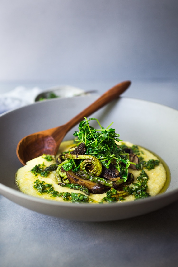 Creamy Polenta with Spring Veggies and Gremolata - a simple healthy VEGAN recipe featuring vibrant spring produce that can be made in under 30 minutes. Vegan & Gluten Free! #creamypolenta #vegan #springrecipes #asparagus #fiddleheadferns #morel #porcini #softpolenta #veganpolenta 