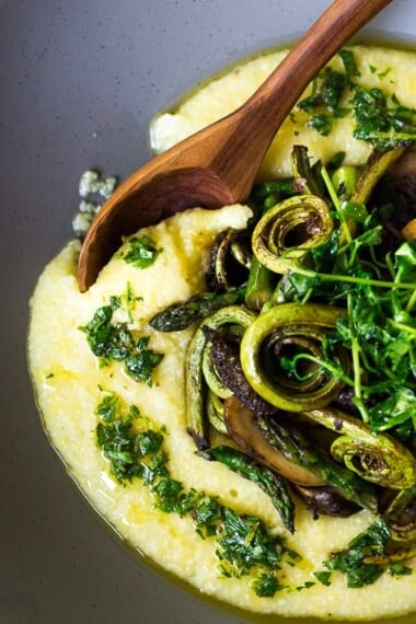 A simple elegant recipe for Creamy Polenta with Spring Veggies and Gremolata -  flavorful and healthy featuring vibrant spring produce that can be made in under 30 minutes. Vegan & Gluten Free! #creamypolenta #vegan #springrecipes #asparagus #fiddleheadferns #morel #porcini #softpolenta #veganpolenta