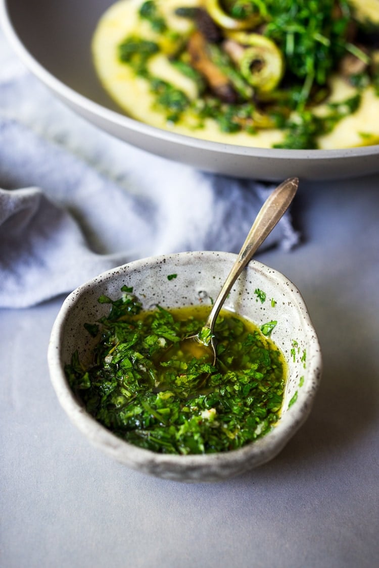 herby gremolata in small ceramic dish with spoon.